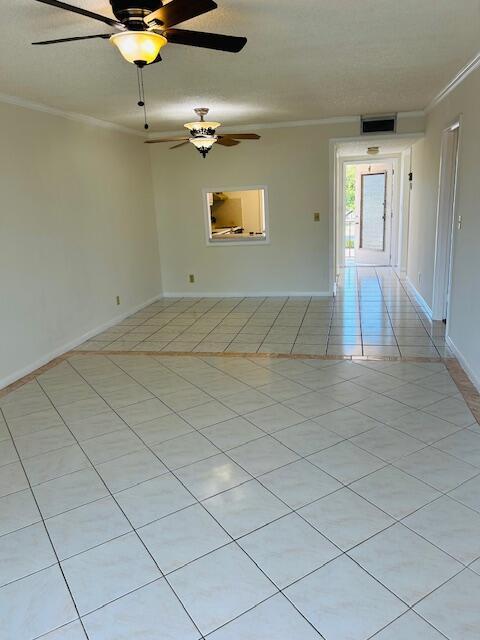 unfurnished room featuring visible vents, crown molding, baseboards, and light tile patterned floors