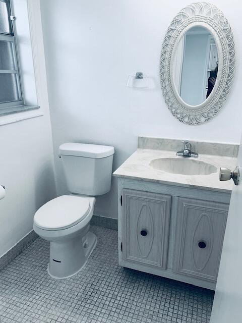 half bathroom featuring toilet, vanity, baseboards, and tile patterned floors