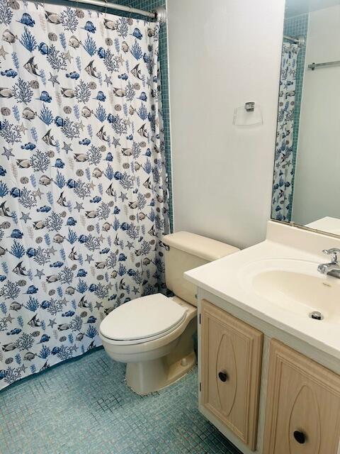 bathroom with toilet, curtained shower, tile patterned flooring, and vanity