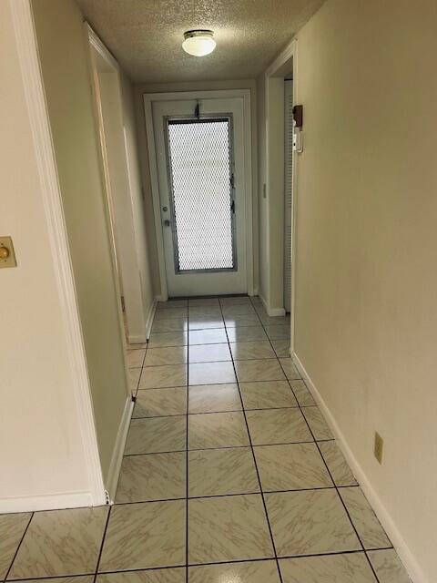 corridor with a textured ceiling and baseboards