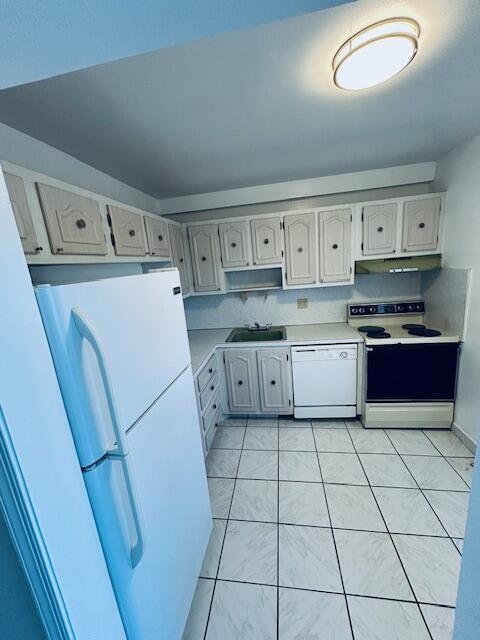 kitchen with light tile patterned floors, light countertops, a sink, white appliances, and under cabinet range hood