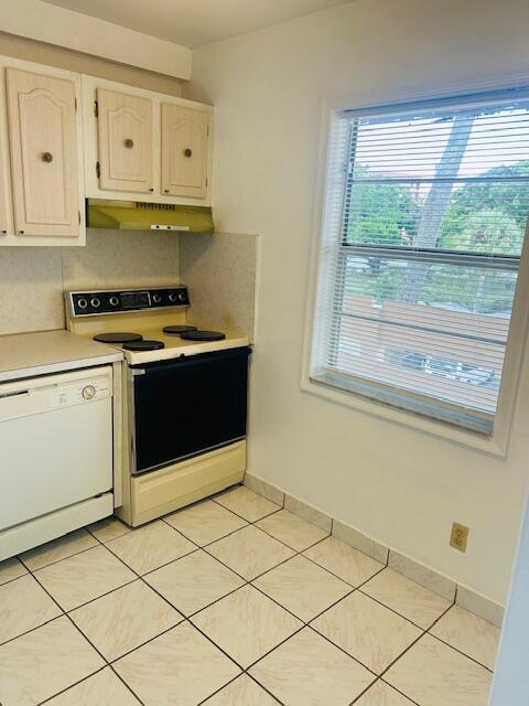 kitchen with range with electric cooktop, white dishwasher, light countertops, under cabinet range hood, and backsplash