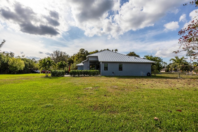 back of property featuring metal roof and a yard