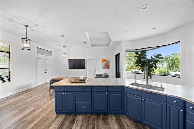 kitchen with light countertops, blue cabinetry, a sink, and decorative light fixtures