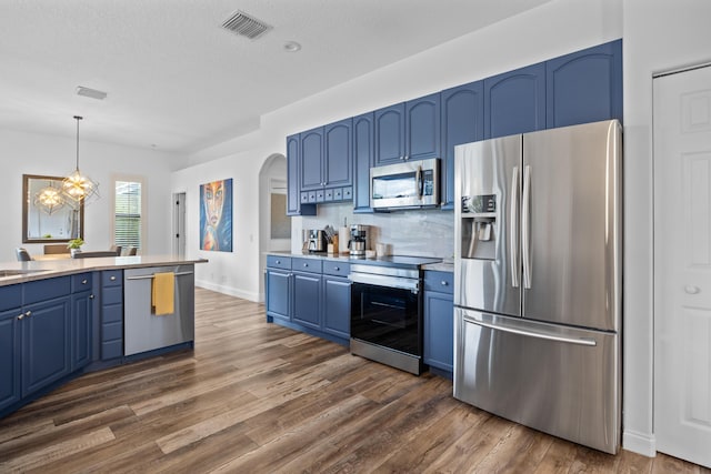 kitchen featuring blue cabinetry, appliances with stainless steel finishes, light countertops, and decorative light fixtures