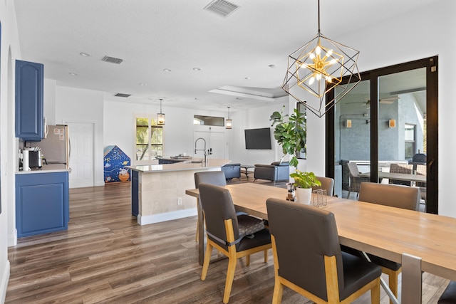 dining space with a chandelier, visible vents, dark wood finished floors, and baseboards