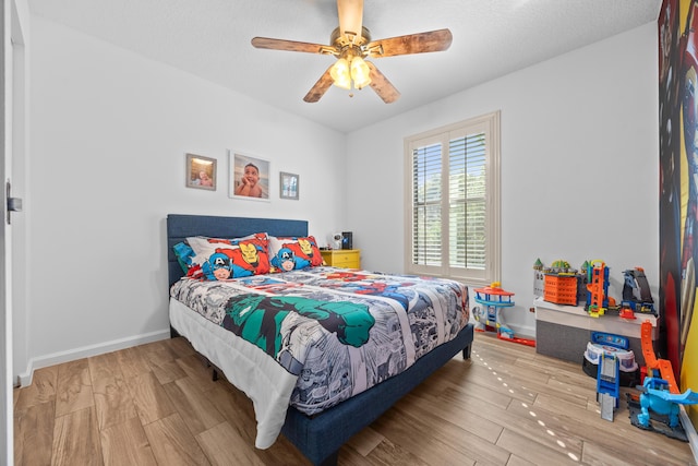 bedroom with ceiling fan, a textured ceiling, baseboards, and wood finished floors