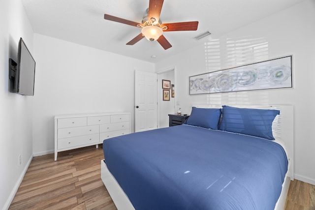 bedroom featuring a ceiling fan, visible vents, baseboards, and wood finished floors