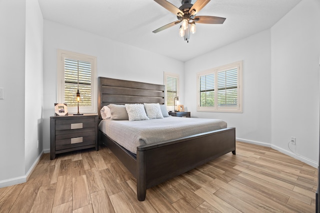 bedroom with a ceiling fan, baseboards, and light wood finished floors