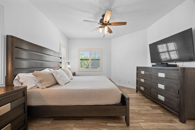 bedroom with baseboards, light wood-style flooring, a ceiling fan, and a textured ceiling