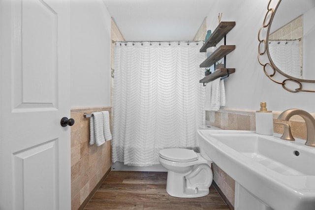 full bath featuring toilet, wood finished floors, a sink, and tile walls