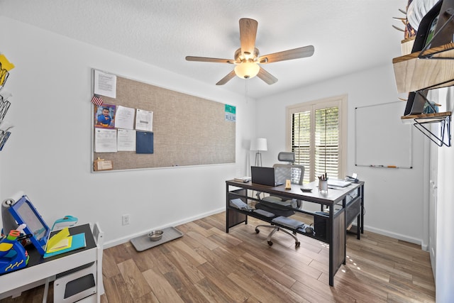 home office featuring a textured ceiling, wood finished floors, a ceiling fan, and baseboards