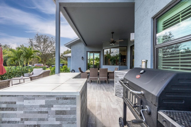 view of patio with ceiling fan, outdoor dining space, area for grilling, and an outdoor bar