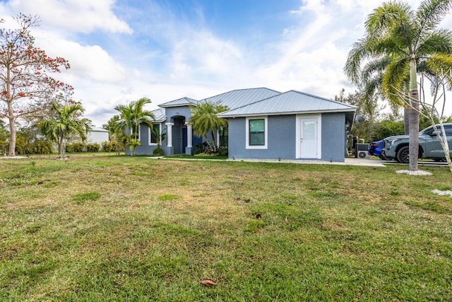 view of front of property with a front yard, metal roof, and stucco siding