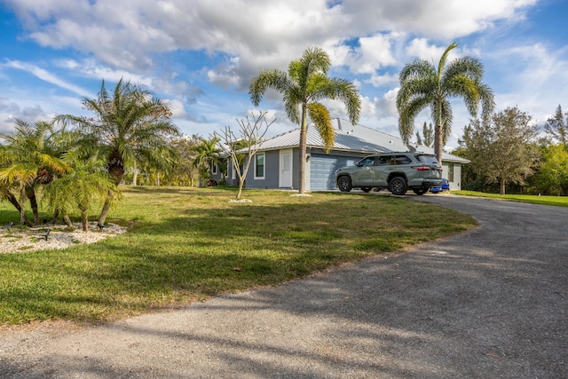 view of side of property with a garage, a yard, aphalt driveway, and metal roof