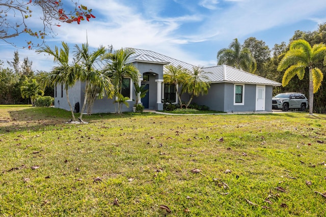 view of front of home featuring a standing seam roof, metal roof, a front lawn, and stucco siding