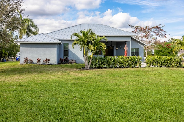 view of front of home featuring stucco siding, metal roof, and a front yard