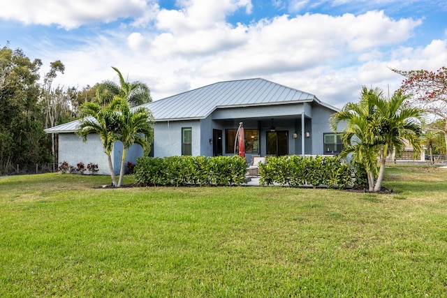 view of front of property featuring metal roof, ceiling fan, a front lawn, and stucco siding