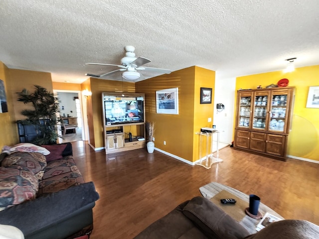 living room featuring a ceiling fan, a textured ceiling, baseboards, and wood finished floors