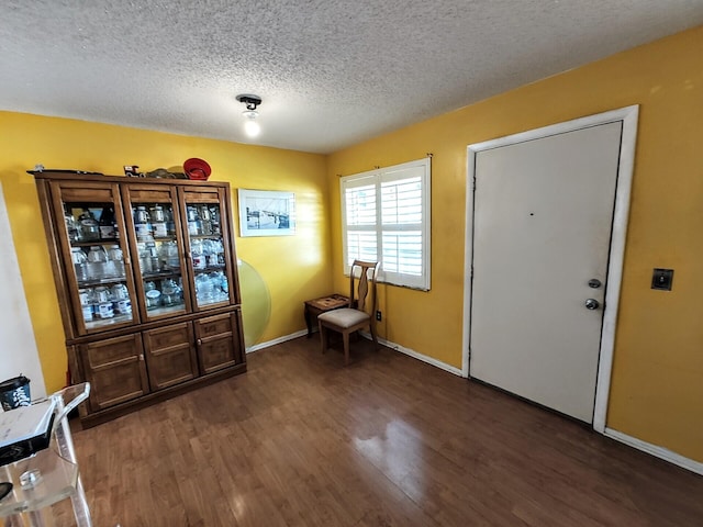 foyer entrance with a textured ceiling, baseboards, and wood finished floors