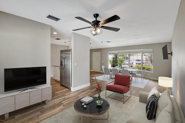 living room featuring light wood-style floors, visible vents, ceiling fan, and baseboards