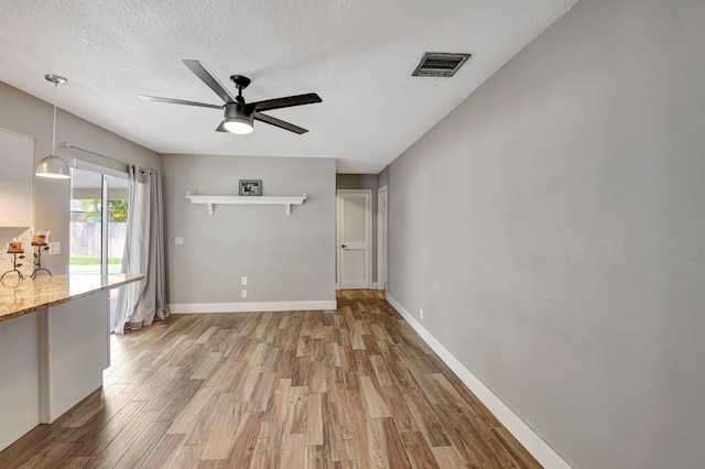 unfurnished room with light wood-style floors, baseboards, visible vents, and a textured ceiling