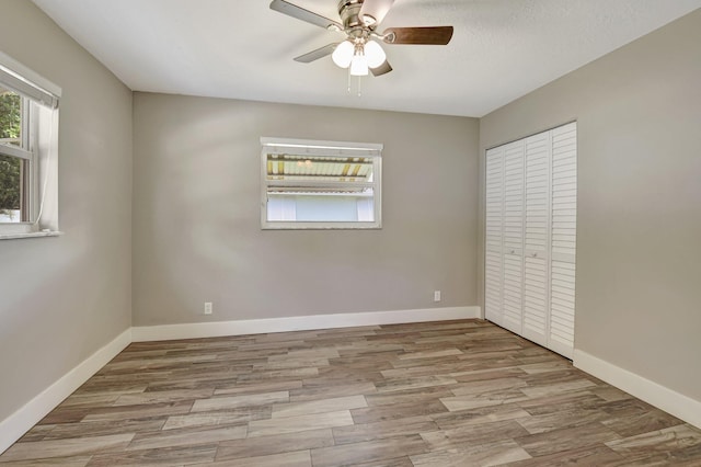 unfurnished bedroom featuring a closet, ceiling fan, baseboards, and wood finished floors