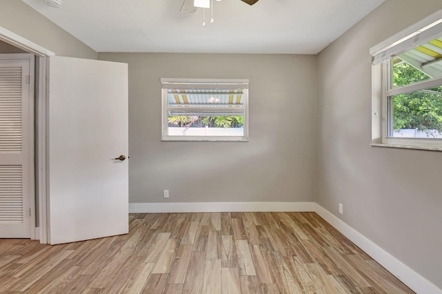 empty room featuring a ceiling fan, wood finished floors, a wealth of natural light, and baseboards