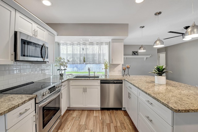 kitchen featuring stainless steel appliances, a peninsula, a sink, and white cabinetry