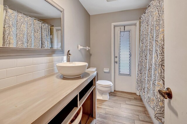 full bath featuring decorative backsplash, wood tiled floor, vanity, and toilet