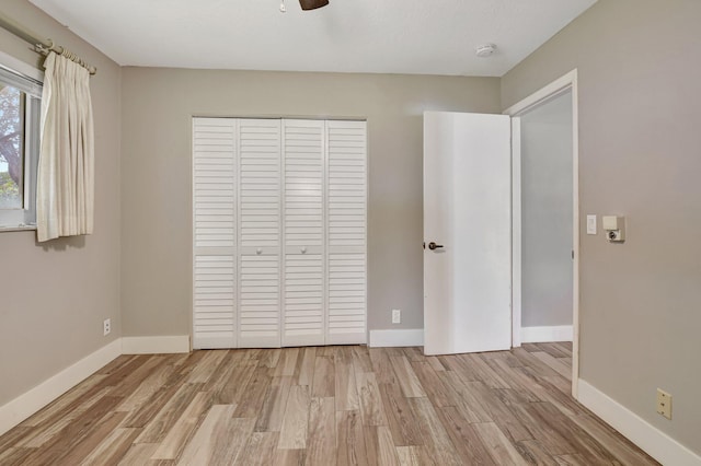 unfurnished bedroom with a closet, wood finished floors, a ceiling fan, and baseboards