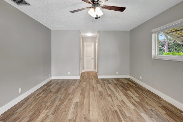 spare room featuring visible vents, a textured ceiling, baseboards, and wood finished floors