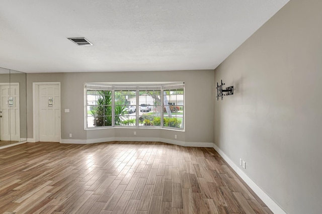 spare room featuring baseboards, visible vents, and wood finished floors