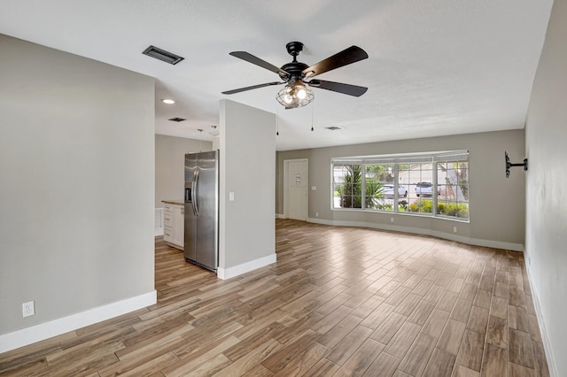 empty room featuring light wood-style floors, visible vents, ceiling fan, and baseboards