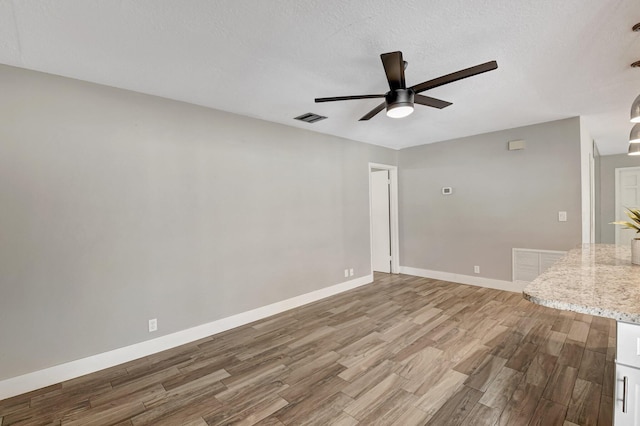 empty room with wood finished floors, visible vents, and baseboards