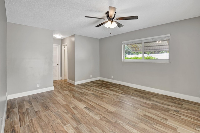 empty room with a textured ceiling, ceiling fan, wood finished floors, and baseboards