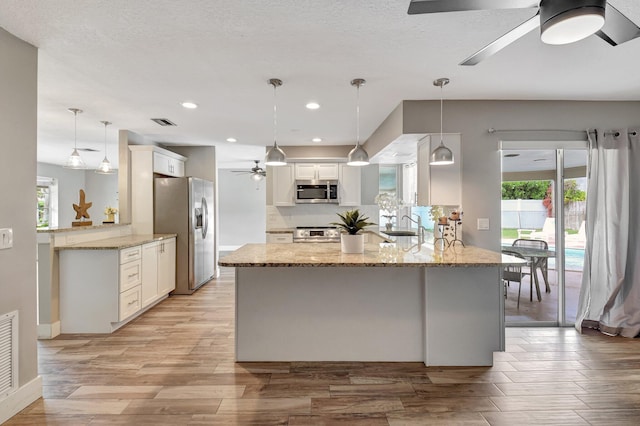 kitchen featuring stainless steel appliances, a peninsula, white cabinetry, visible vents, and light stone countertops