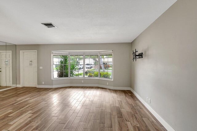 empty room featuring baseboards, visible vents, and wood finished floors