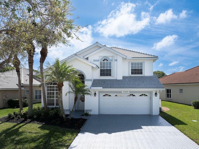 view of front facade featuring an attached garage, a tile roof, decorative driveway, stucco siding, and a front yard