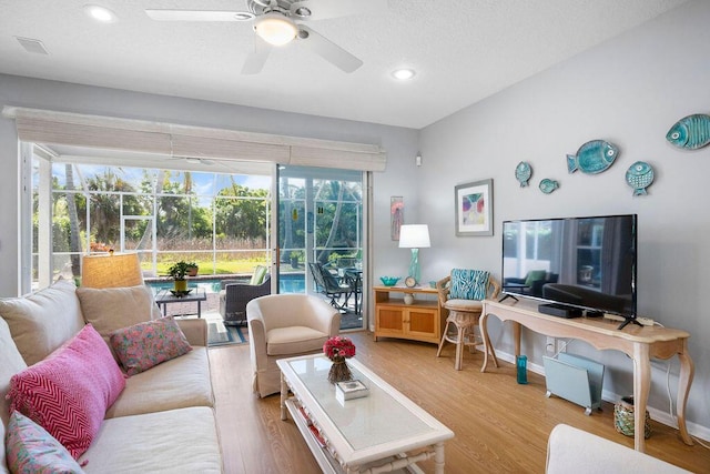 living area with a sunroom, a ceiling fan, baseboards, and wood finished floors