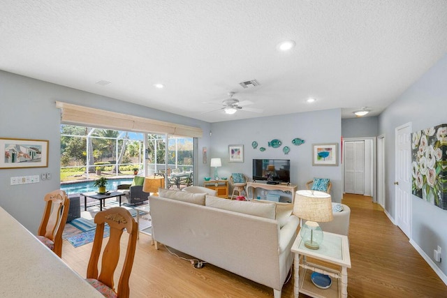 living area featuring light wood-type flooring, a sunroom, visible vents, and ceiling fan