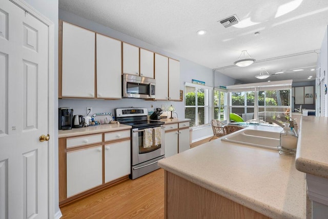 kitchen with visible vents, white cabinets, appliances with stainless steel finishes, light countertops, and a sink