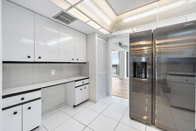 kitchen with light countertops, white cabinets, stainless steel fridge with ice dispenser, and visible vents