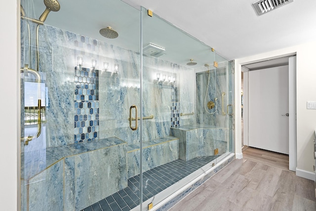 bathroom with a shower stall, wood finished floors, and visible vents