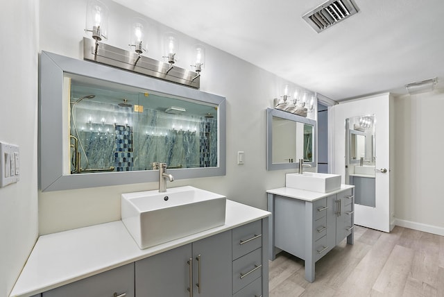 full bathroom with visible vents, a shower stall, wood finished floors, and a sink