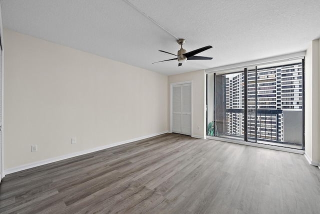 unfurnished room featuring a ceiling fan, wood finished floors, baseboards, and a textured ceiling
