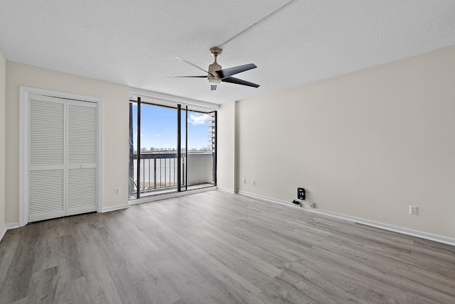 interior space featuring a wall of windows, access to exterior, wood finished floors, and baseboards