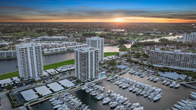 aerial view at dusk featuring a water view and a city view