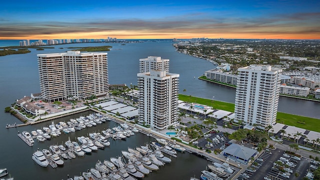 aerial view at dusk featuring a water view and a view of city