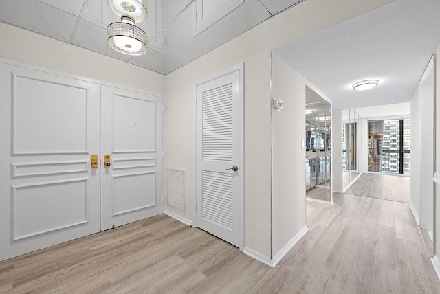 hallway with wood finished floors, visible vents, and baseboards
